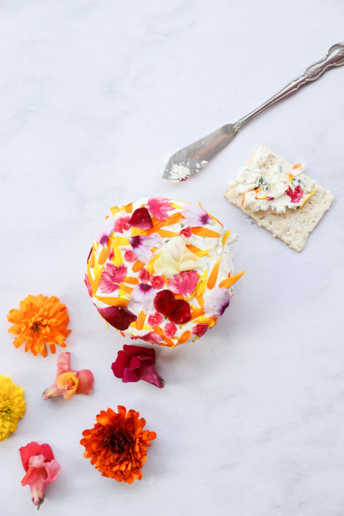 Goat cheese spread topped with edible flowers and fresh herbs