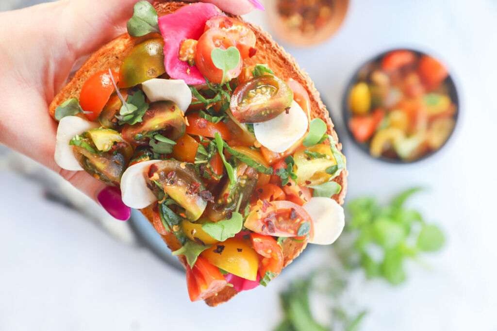 Mediterranean garden toast with edible flowers, tomatoes, and basil