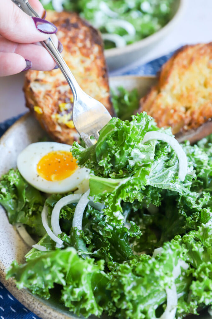 Kale Caesar salad topped with a poached egg and Parmesan shavings