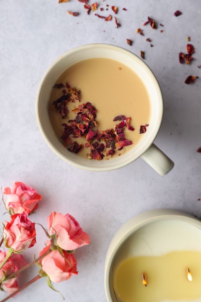 A cup of Rose Petal Milk Tea surrounded by rose petals