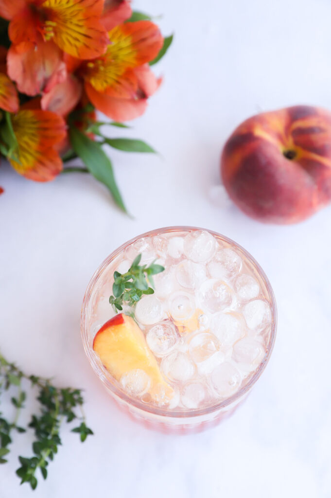 Sparkling peach and thyme mocktail with fresh peach slices and thyme sprigs