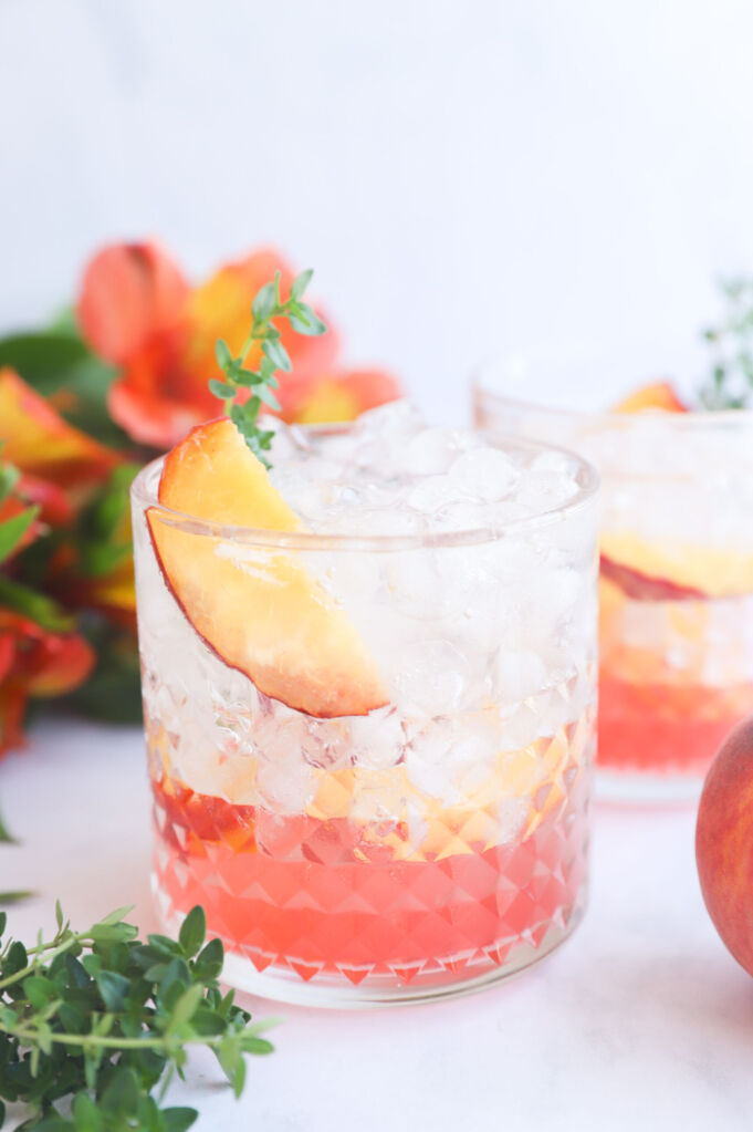 Sparkling peach and thyme mocktail with fresh peach slices and thyme sprigs