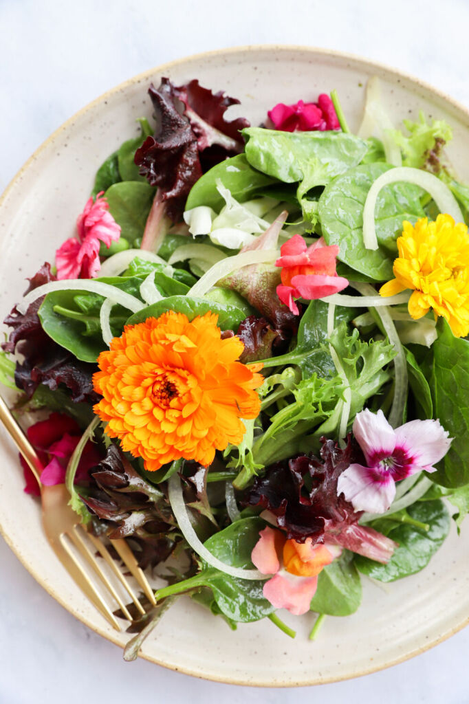 Fresh garden salad topped with edible flowers and a light apple cider vinegar dressing