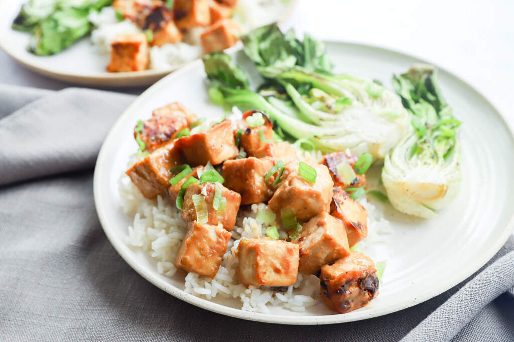 Close-up of baked miso tofu with bok choy on a rustic plate for hormone balance