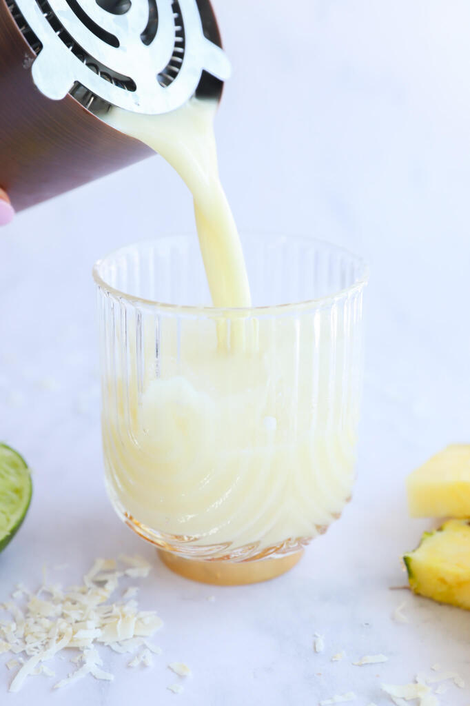 Tropical pineapple coconut water mocktail with a garnish of pineapple and coconut flakes