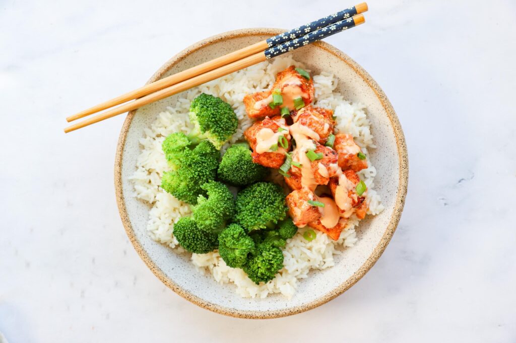 Air fryer salmon bites arranged on a plate with bang bang sauce