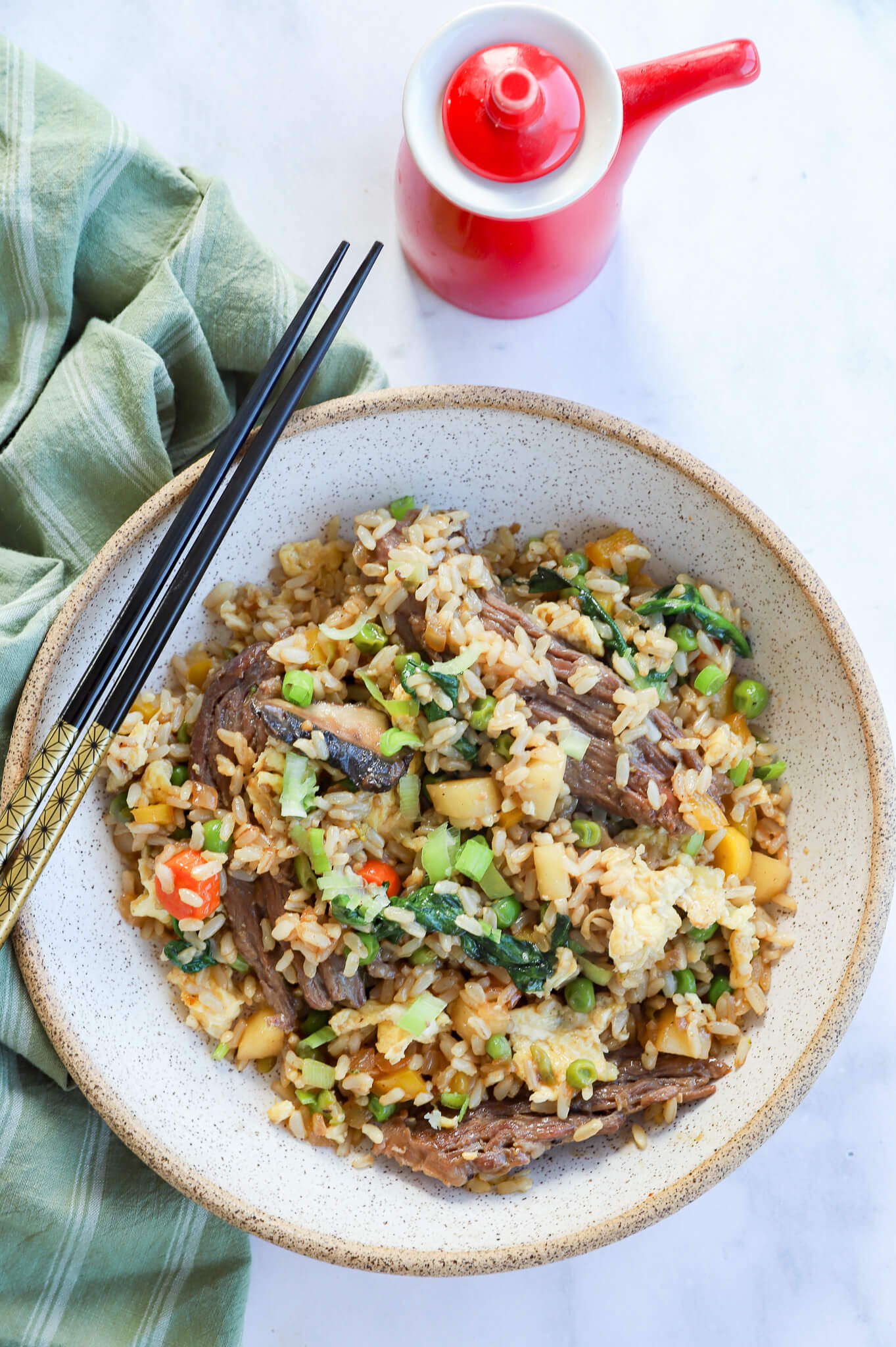 A bowl of beef fried rice with vegetables and sesame seeds