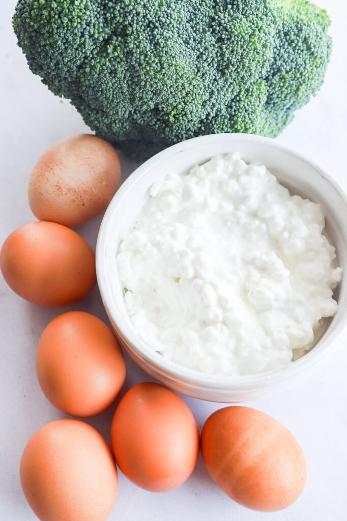 Overhead shot of ingredients for broccoli egg bites, including cottage cheese, eggs, and broccoli