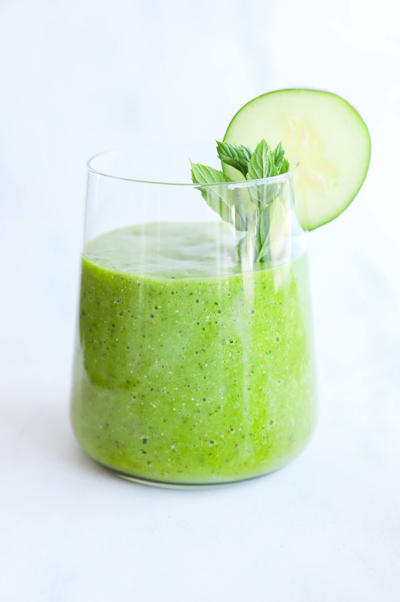 Glass of refreshing cucumber mint matcha smoothie garnished with mint leaves