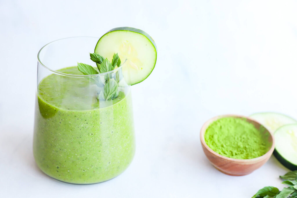 A landscape shot of cucumber mint matcha smoothie with cucumber slices and mint leaves