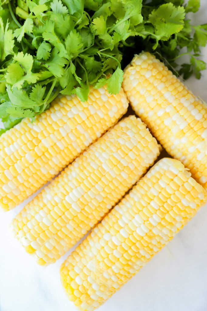 Overhead shot of ingredients for Mexican street corn dip, including corn, cheese, lime, and spices.