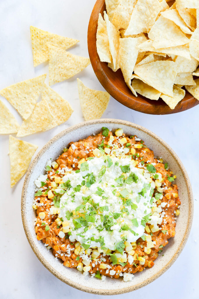 Close-up of a bowl filled with Mexican street corn dip, garnished with cilantro and cotija cheese.