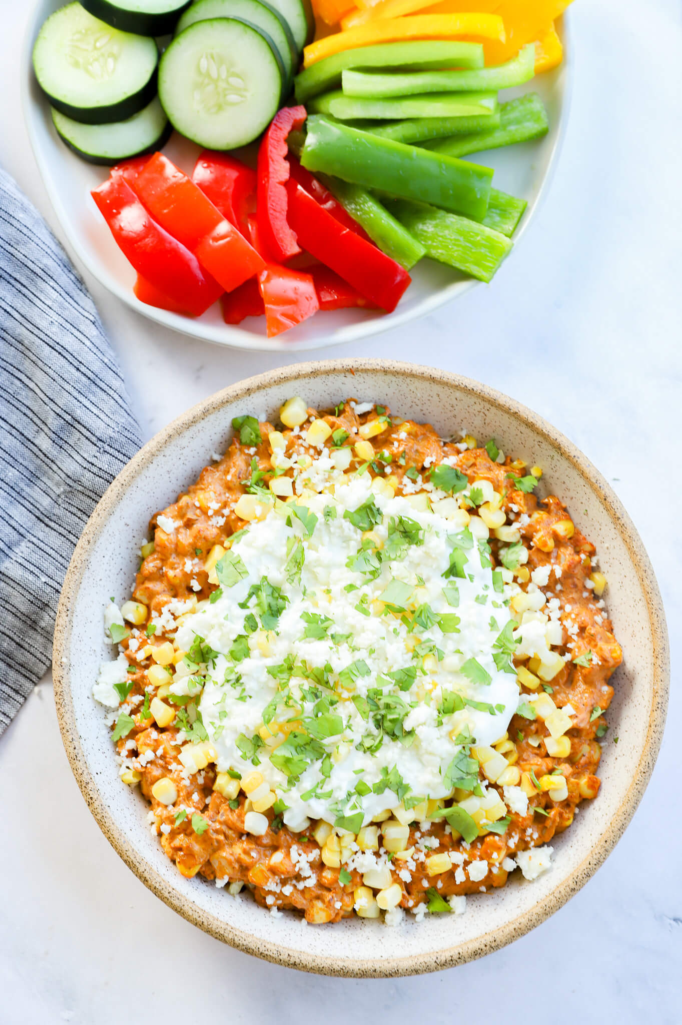 A vibrant bowl of Mexican street corn dip topped with cilantro and spices.